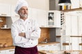 Attractive Caucasian chef standing with arms crossed in a restaurant kitchen