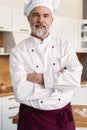 Attractive Caucasian chef standing with arms crossed in a restaurant kitchen