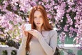 Attractive caucasian female holding cream jar in hands posing in spring garden, beauty concept Royalty Free Stock Photo