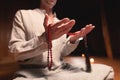 An attractive caucasian man in a lotus position sits in a dark meditation room and holds a red rosary for prayer in his Royalty Free Stock Photo