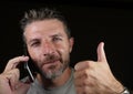 Attractive Caucasian man talking on mobile phone having business conversation isolated on black background giving thumb up in Royalty Free Stock Photo