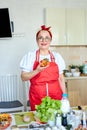 Attractive caucasian senior woman in red apron enjoy eating tasty pizza after cooking