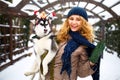 Attractive authentic caucasian woman hugs funny malamute dog wearing santa dear christmas antlers. Curly smiling female Royalty Free Stock Photo