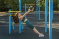 Attractive Caucasian woman pulls up on gymnastic rings during a workout on a street sports ground. Royalty Free Stock Photo