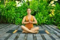 Attractive woman sitting on yoga mat, meditating, practicing yoga and pranayama. Lotus pose. Hands in namaste mudra. Bali, Royalty Free Stock Photo