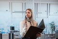 Attractive woman standing alone at the office and hold folder for paper documents Royalty Free Stock Photo