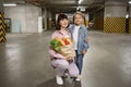 Mother and daughter in casual clothes holding paper bag with vegetables. Royalty Free Stock Photo