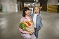 Mother and daughter in casual clothes holding paper bag with vegetables. Royalty Free Stock Photo