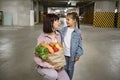 Mother and daughter in casual clothes holding paper bag with vegetables. Royalty Free Stock Photo