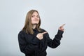 Attractive caucasian young woman pointing fingers aside, looking at camera. Royalty Free Stock Photo