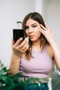 Attractive caucasian young woman holding cosmetic mirror in hand and looking on herself Royalty Free Stock Photo