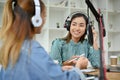 Charming Asian female radio host or podcaster interviewing her female guest