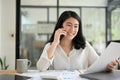 Asian young businesswoman talking on the phone while looking the details on her report Royalty Free Stock Photo