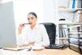 Attractive charming businesswoman sitting at her workplace holding pen Royalty Free Stock Photo