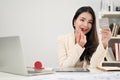 Attractive Asian businesswoman applying makeup on her face at her desk in the office Royalty Free Stock Photo