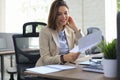 Attractive cheerful business woman checking paper documents in office, working on laptop Royalty Free Stock Photo