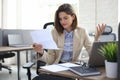 Attractive cheerful business woman checking paper documents in office, working on laptop Royalty Free Stock Photo