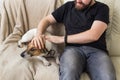 Close-up of male in casual t shirt sitting on couch favourite pet. Happy bearded man with his jack russell terrier. Pet