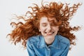 Attractive cheerful redhead girl with flying curly hair smiling laughing with closed eyes over white background. Royalty Free Stock Photo