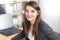 cheerful young businesswoman working on laptop and smiling while sitting at her desk office Royalty Free Stock Photo