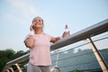 Attractive cheerful young Hispanic woman in pink t-shirt talking on mobile phone while resting on a city bridge after early Royalty Free Stock Photo