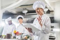 attractive chef holding recipe book and showing idea gesture