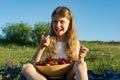 Attractive child girl eating strawberry. Nature background, green meadow, country style Royalty Free Stock Photo