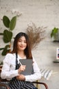 Coffee shop entrepreneur holding digital tablet and stylus pen sitting at her cafe. Royalty Free Stock Photo