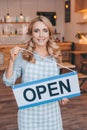attractive coffee shop owner in apron holding sign open and smiling Royalty Free Stock Photo