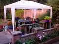 Plastic garden chairs and table under a white plastic gazebo on a small piece of wooden decking Royalty Free Stock Photo