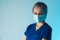 Attractive concentrated european female family doctor in a surgical mask and a blue medical t-shirt looking directly on Royalty Free Stock Photo