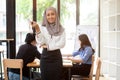 An attractive Muslim businesswoman is smiling at the camera while standing in the meeting room Royalty Free Stock Photo