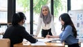 A confident Asian Muslim businesswoman stands in front of the meeting, leading the meeting Royalty Free Stock Photo