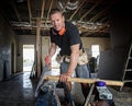 Attractive and confident constructor carpenter or builder man working cutting wood with manual saw at industrial construction site Royalty Free Stock Photo