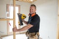 Attractive and confident constructor carpenter or builder man working wood with electric drill at industrial construction site Royalty Free Stock Photo