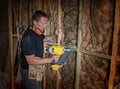 Confident constructor carpenter or builder man working wood with electric drill at industrial construction site in installation a