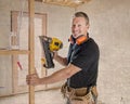 Confident constructor carpenter or builder man working wood with electric drill at industrial construction site in installation a Royalty Free Stock Photo