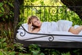 Attractive, content, young, sexy, cute, brunette woman lying smiling outdoors relaxed in bed, with fresh, white sheets and pillows Royalty Free Stock Photo