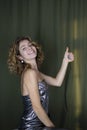 Portrait of an attractive coquettish cheerful girl 16-18 years old with curly hair, showing thumbs up Royalty Free Stock Photo