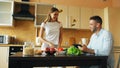 Attractive couple chatting in the kitchen early morning. Handsome man using tablet while his girlfriend cooking Royalty Free Stock Photo