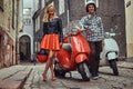 Attractive couple, a handsome man and female standing on an old street with two retro scooters. Royalty Free Stock Photo