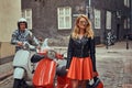 Attractive couple, a handsome man and female standing on an old street with two retro scooters. Royalty Free Stock Photo