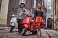 Attractive couple, a handsome man and female standing on an old street with two retro scooters. Royalty Free Stock Photo