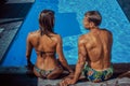 An attractive couple, handsome muscular male and woman sitting near the pool and enjoying a vacation. Royalty Free Stock Photo