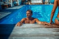 An attractive couple, handsome muscular male and woman sitting near the pool and enjoying a vacation. Royalty Free Stock Photo