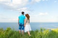 Attractive couple holding each other in hand and looking at lake and blue sky with clouds Royalty Free Stock Photo