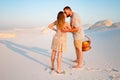 Attractive couple kissing on the white sand beach or in the desert or in the sand dunes, guy and a girl with a basket in their han Royalty Free Stock Photo