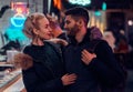 Attractive couple in love. A beautiful girl hugging her boyfriend standing in the night on the street. Royalty Free Stock Photo