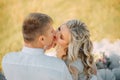 Attractive couple of lovers sitting on the grass in the meadow, guy gently holds his girl by the chin and stretches to Royalty Free Stock Photo