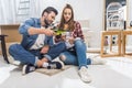 Young attractive couple sitting on floor at home and pouring champagne Royalty Free Stock Photo